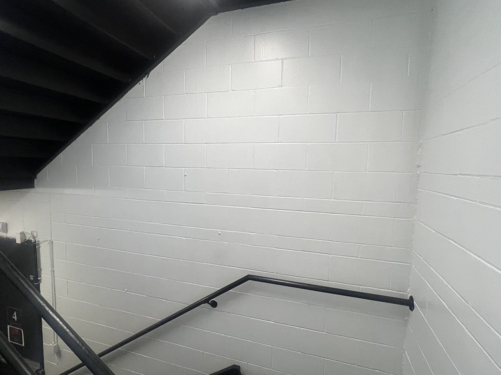 White painted concrete block and shiplap walls in interior space with black metal railing