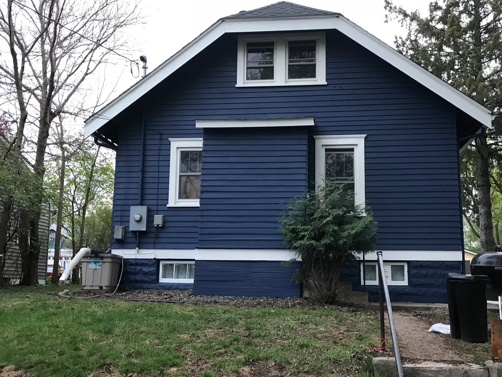 Dark blue painted house exterior with white trim, windows, and gable roof
