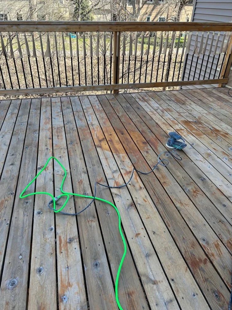 Weathered wood deck with vertical metal railing during staining restoration work
