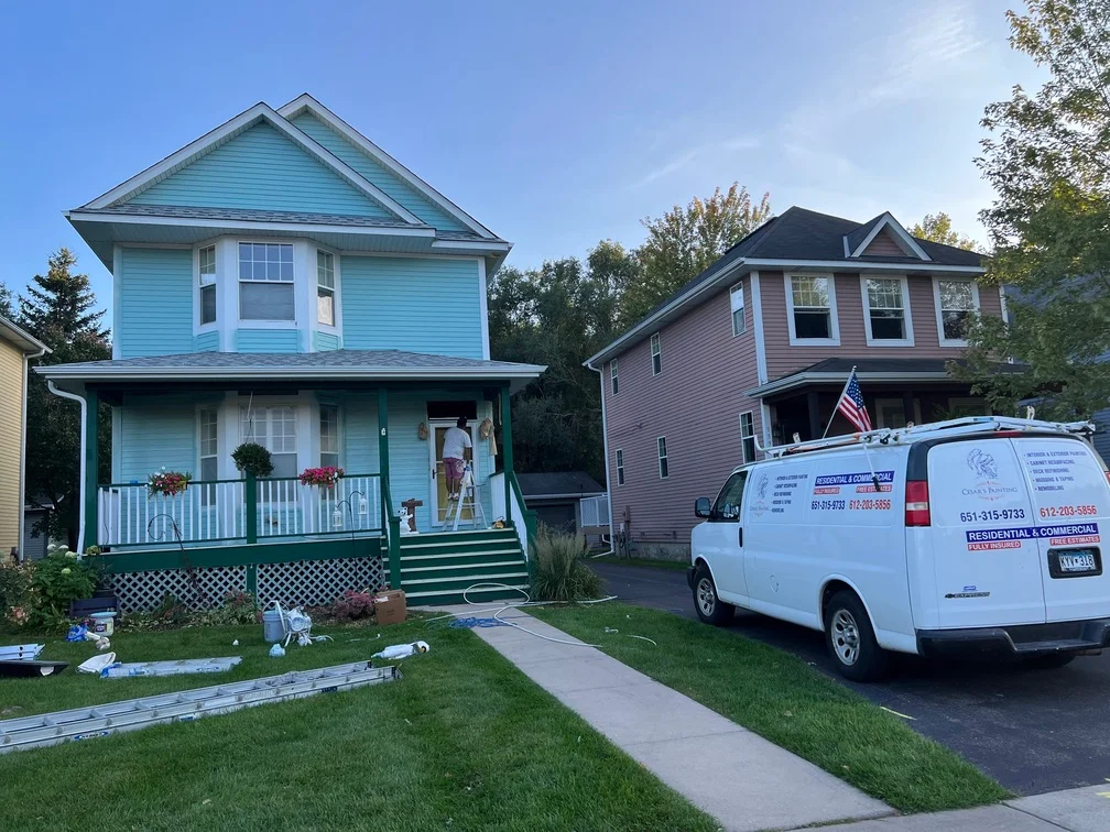 Light blue two-story house with white trim, painted siding and porch railings