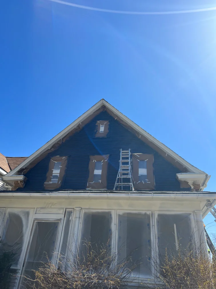 Blue gable siding with white trim and window frames on residential home exterior