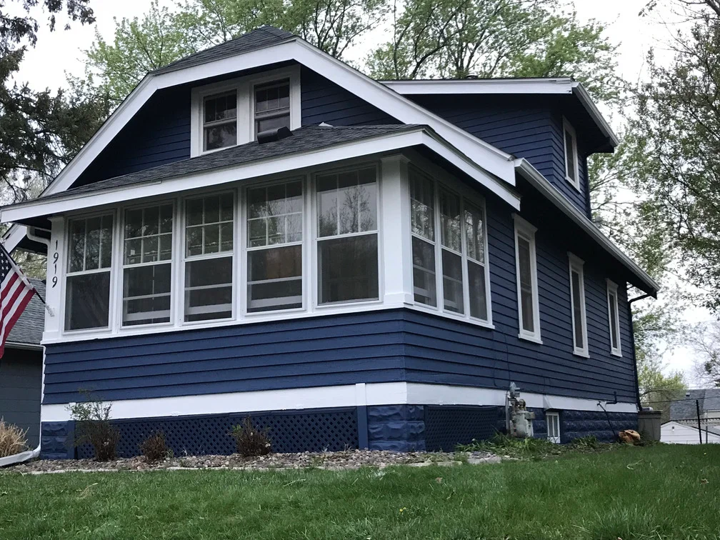 Navy blue and white painted house exterior with white-trimmed windows and fresh siding paint