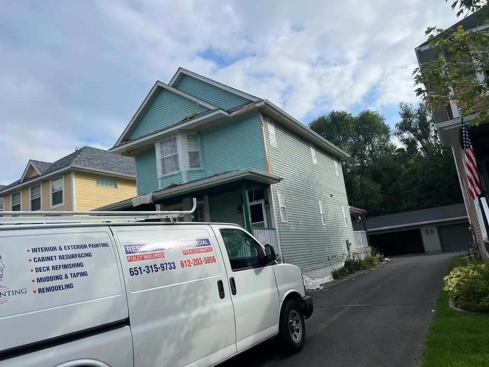 Two-story house with turquoise and white vinyl siding exterior paint