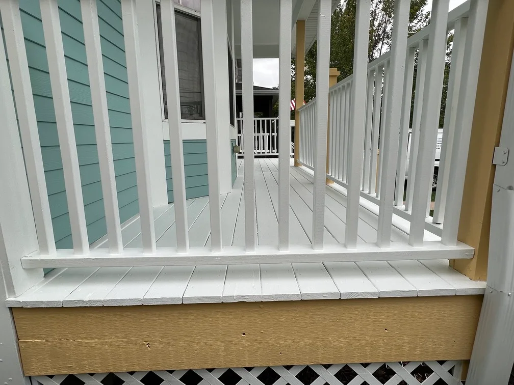 White painted porch railings and trim with turquoise siding and white deck boards