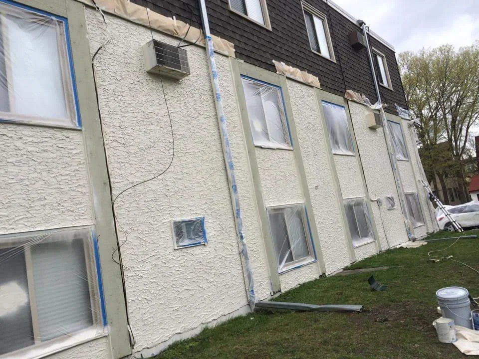 Cream stucco exterior with blue-trimmed windows and doors, freshly painted residential building facade