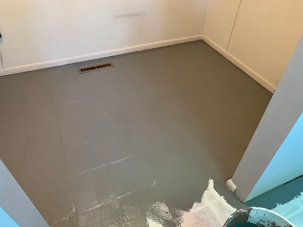 Gray epoxy floor coating with white trim and baseboards in prepared interior room