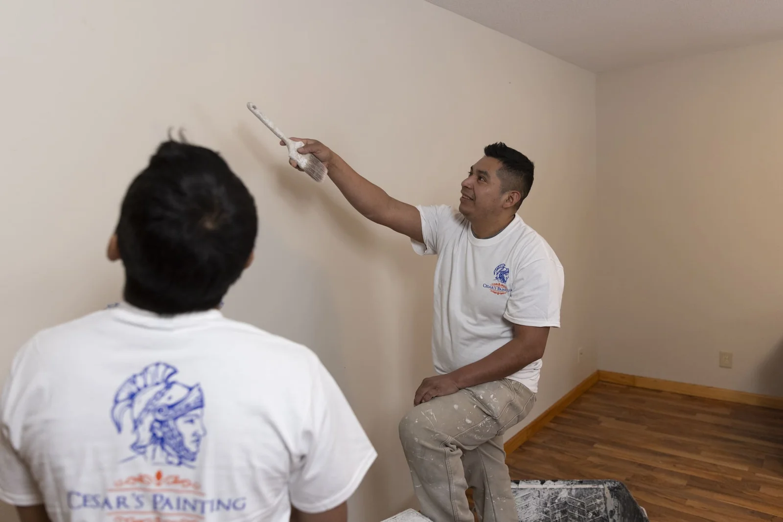Painter applying finish coat to interior drywall wall with brush