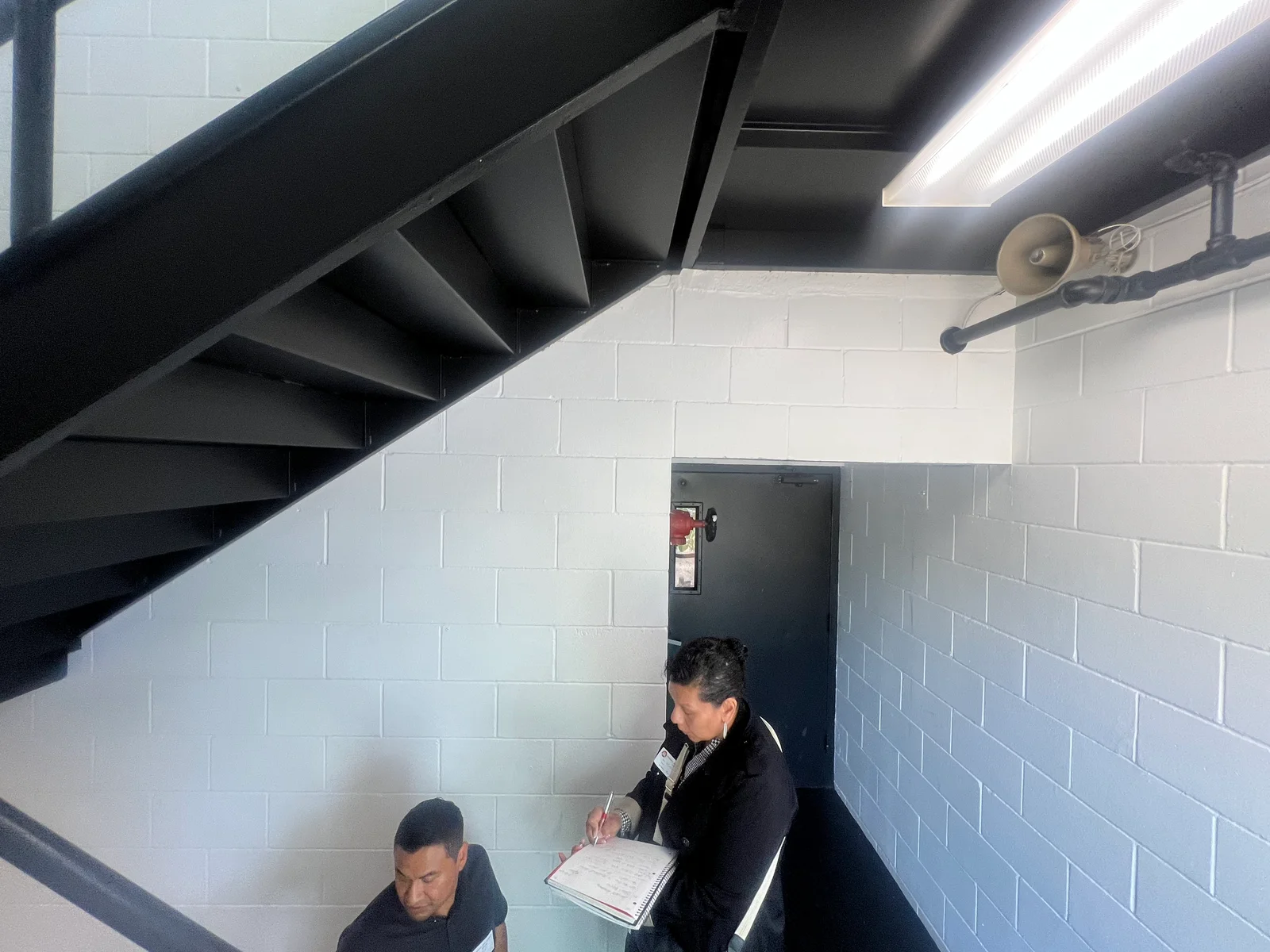 White painted concrete block walls with black metal staircase and LED lighting in commercial interior