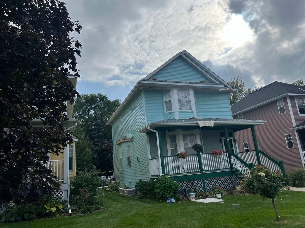 Two-story house with light blue siding, white trim, and painted front porch railings