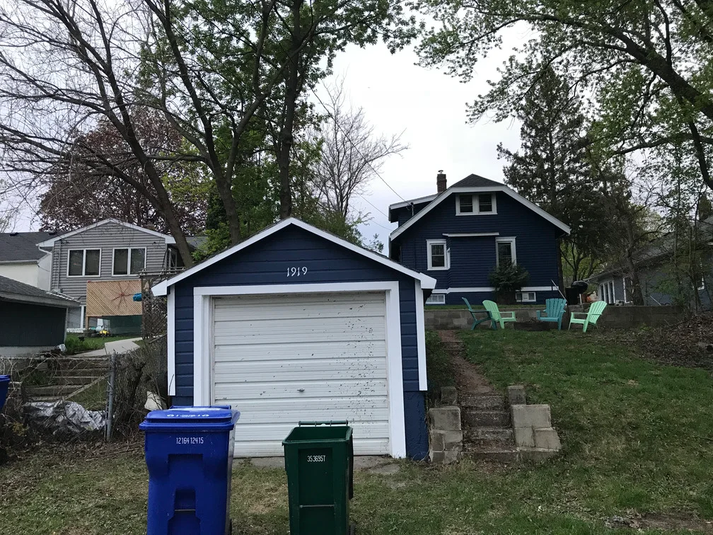 Navy blue garage with white trim and garage door, freshly painted exterior siding