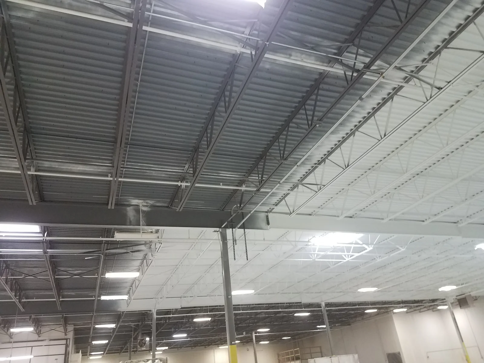 Industrial warehouse interior with painted corrugated metal ceiling panels and steel beam structure