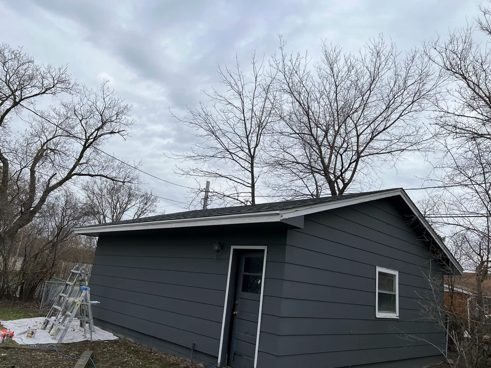 Dark gray painted house exterior with horizontal siding, white trim, and new roof line