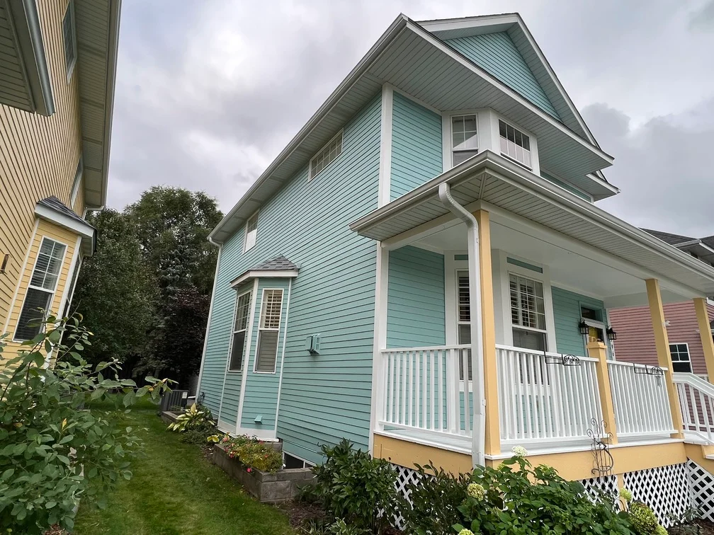 Two-story home with light blue siding, white trim, and covered porch with white railings