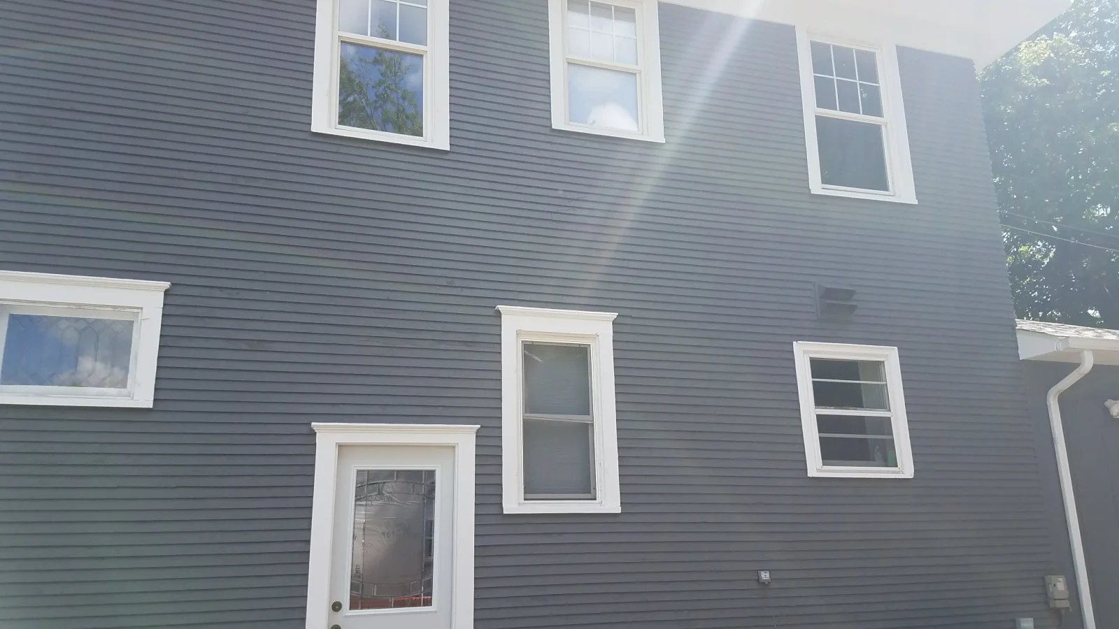 Gray vinyl siding with white-trimmed windows and doors on residential home exterior
