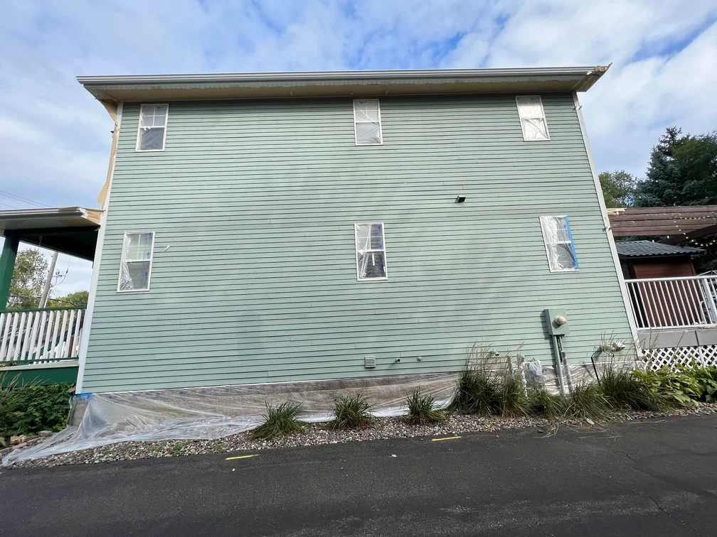 Two-story house with freshly painted light green horizontal vinyl siding and white trim