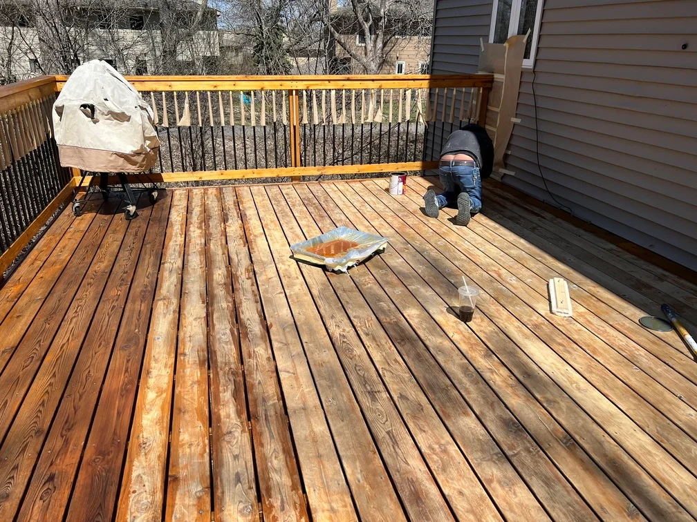 Wooden deck with newly stained boards and yellow railings during refinishing project