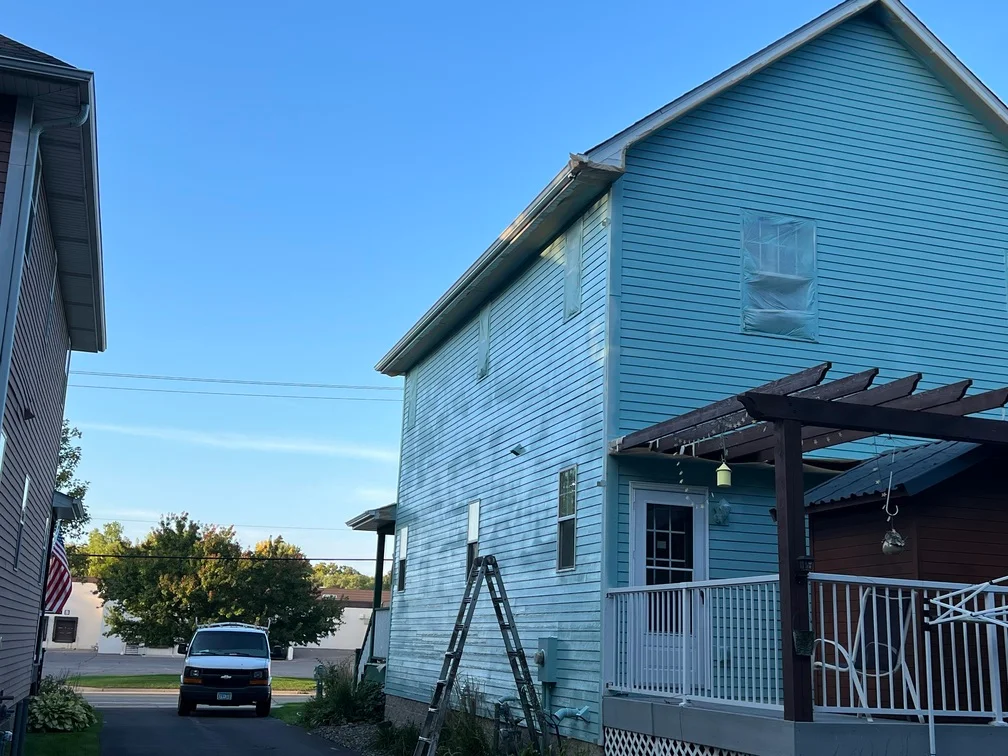 Light blue painted residential house with horizontal vinyl siding and white trim