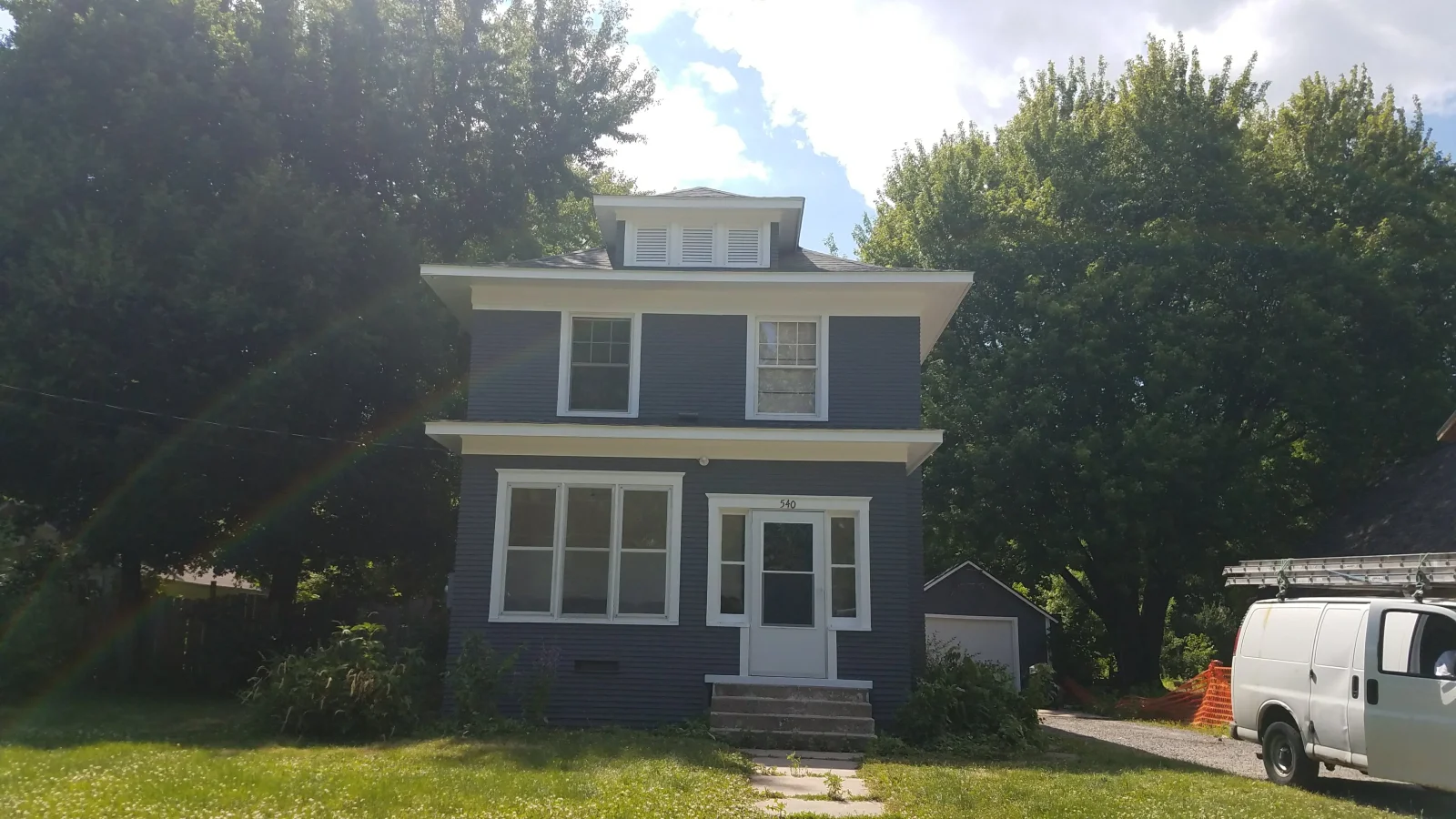 Two-story house with dark blue siding, white trim, painted garage and entry doors