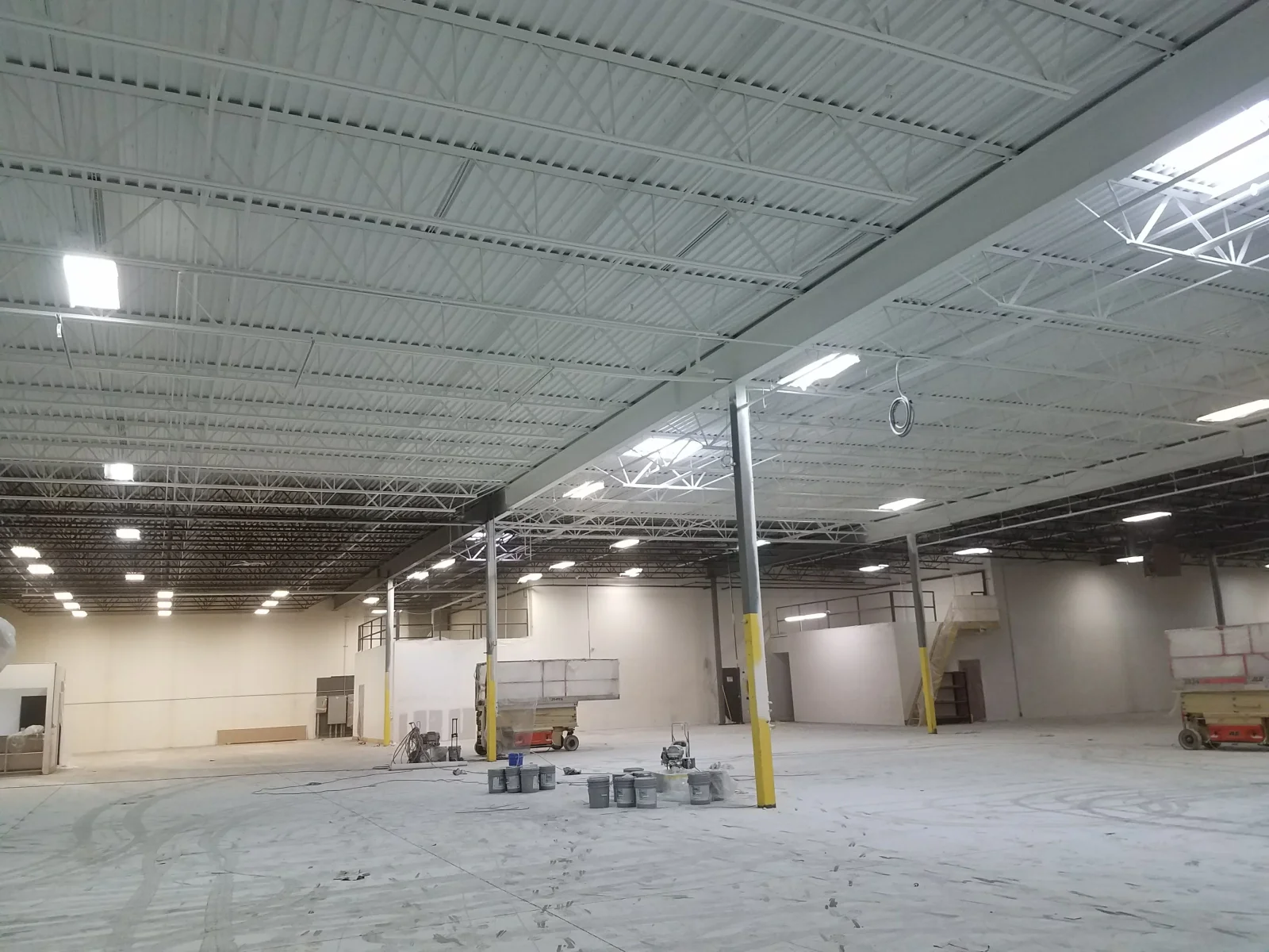 Industrial warehouse interior with painted drywall partitions, steel support columns, and corrugated metal roof