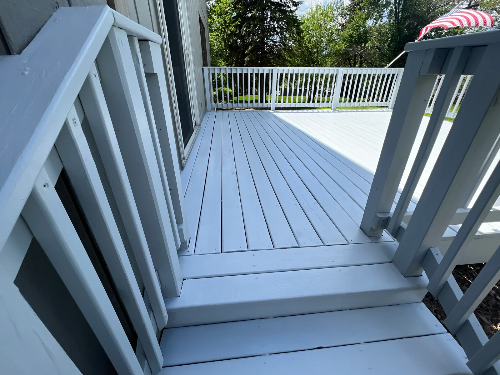 Light gray composite deck with white railings and vertical balusters, finished steps visible