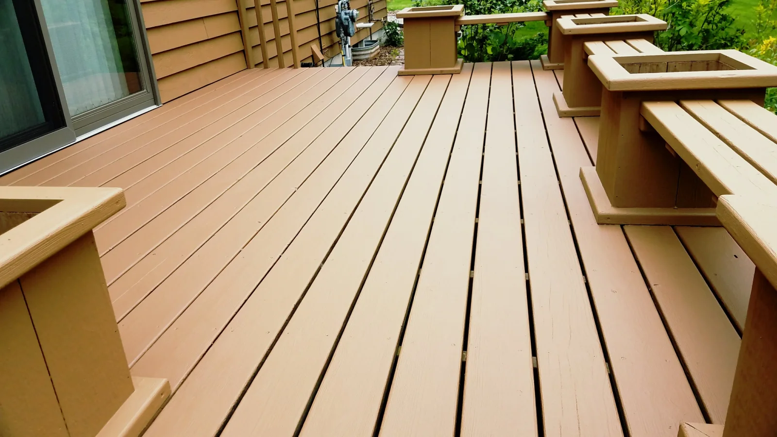 Composite deck with tan boards, dark grooves, and built-in wooden planter boxes