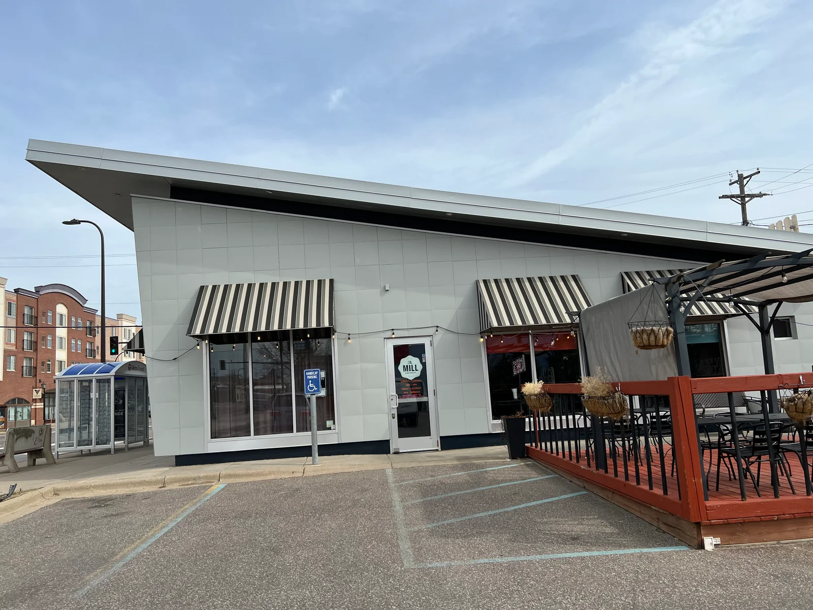 White painted commercial building with black trim, metal panel siding, and striped awnings