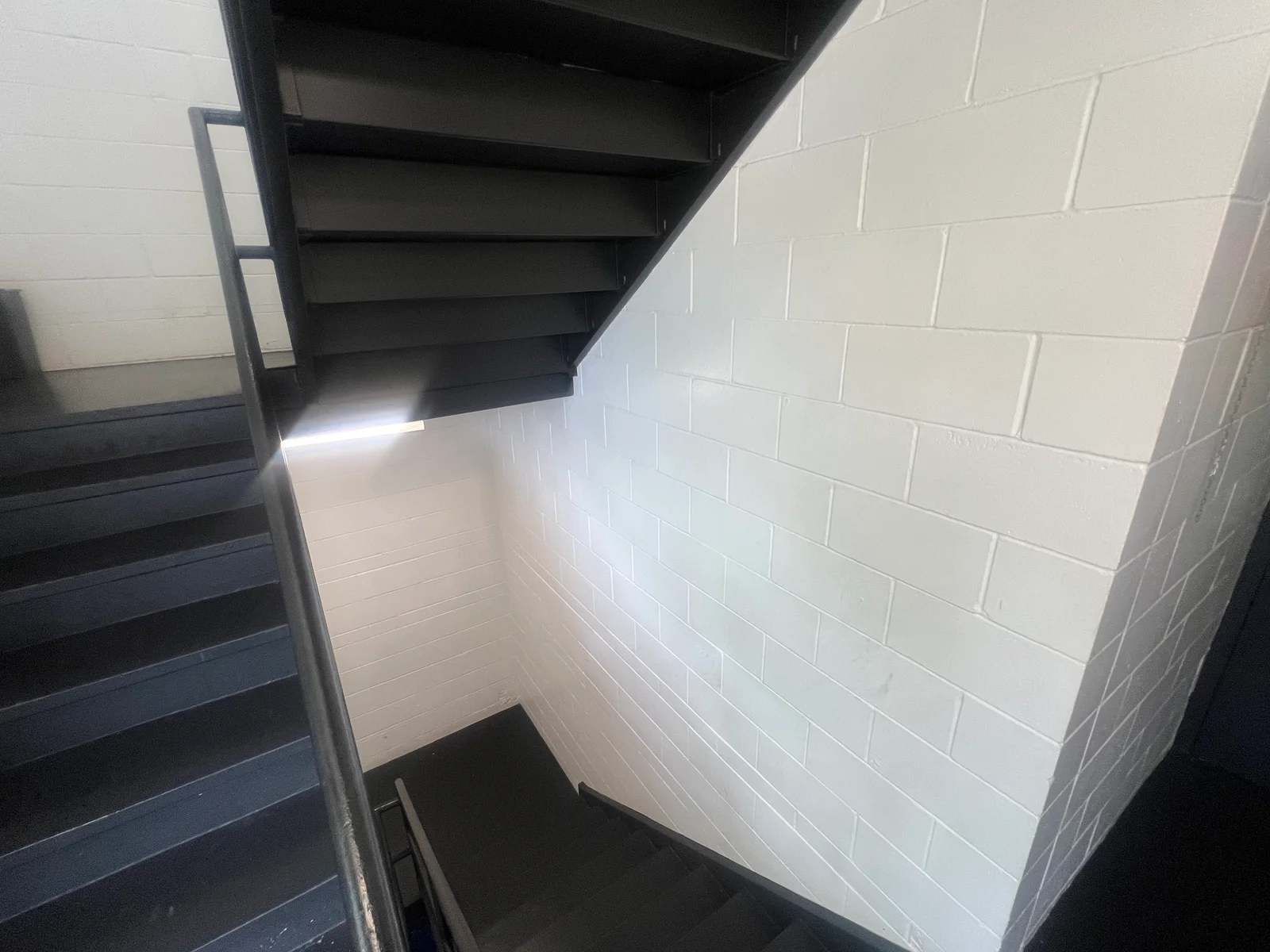 White painted concrete block basement walls with black metal staircase
