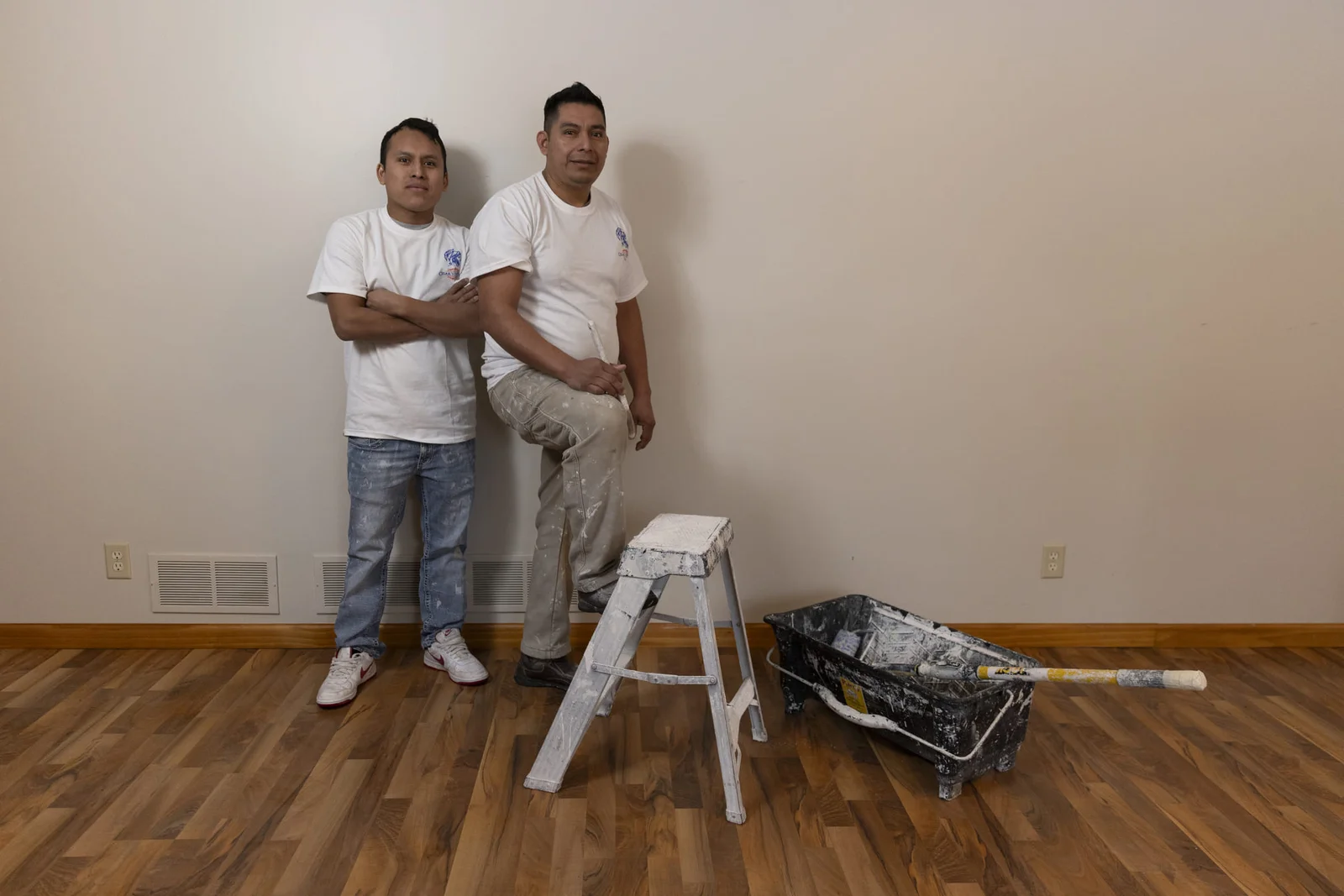 Interior wall painting with fresh paint application and professional tools on wooden floor