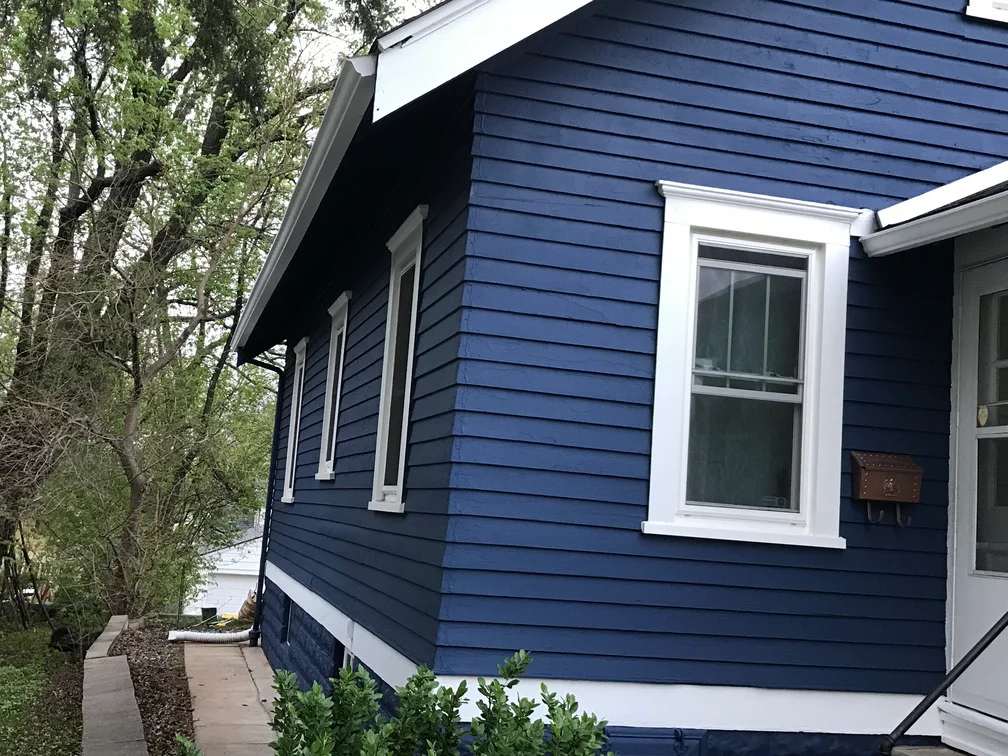 Navy blue painted house exterior with white trim, fiber cement siding, and white-framed windows