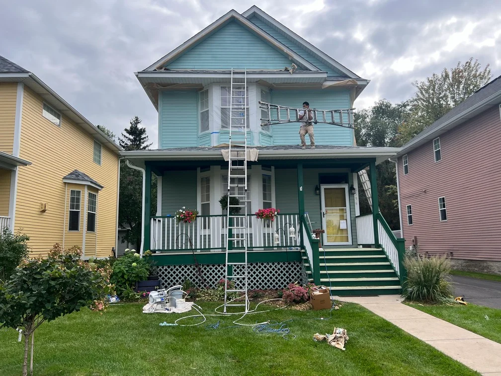 Two-story house with turquoise and green painted siding, white trim, and green porch with white railings