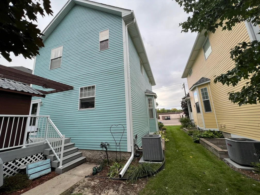 Light blue painted two-story house with white trim, vinyl siding, and white deck railing