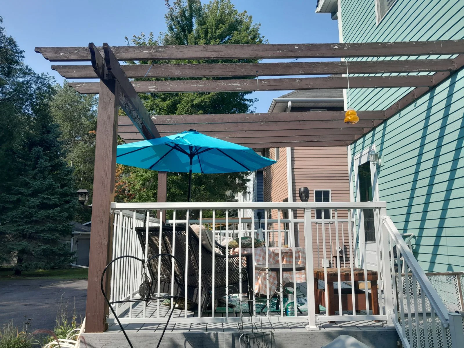 Dark brown stained wood pergola with white painted deck railing and balusters