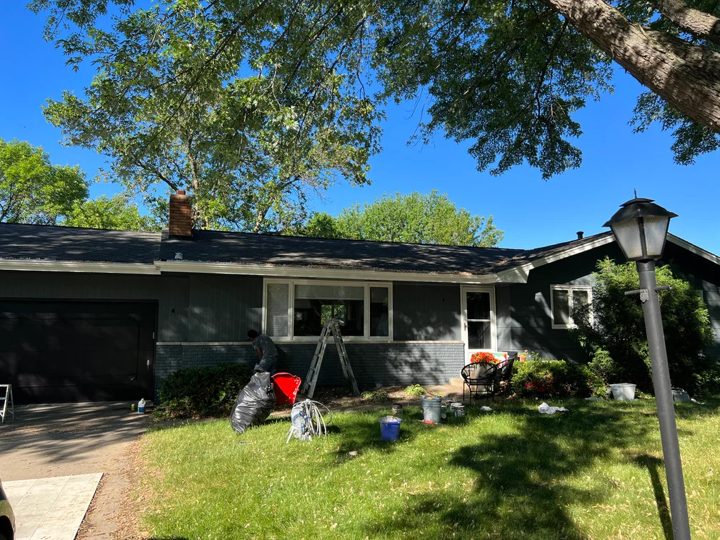 Black painted house exterior with brick foundation and white trim windows