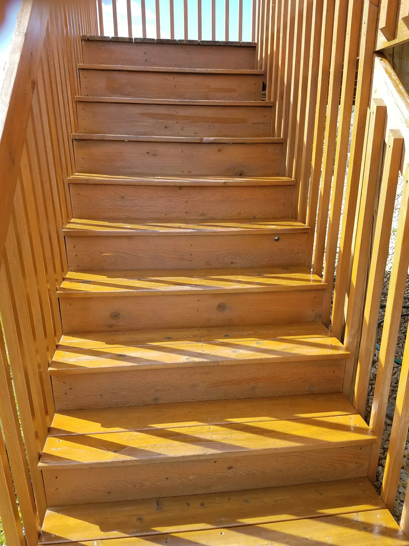 Wooden staircase with medium-brown stain, sealed finish, and brass nosing strips on each tread