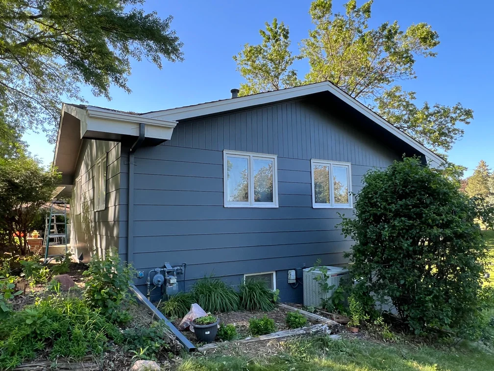 Blue-gray painted horizontal siding on residential home with white trim and windows